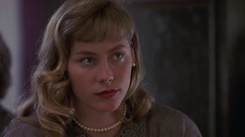 Movie still from “The Big Picture” (1989), directed by Christopher Guest – A young woman with blonde curly hair wearing a pearl necklace; Close Up shot, Over the shoulder angle