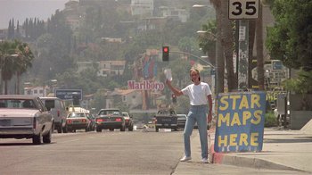 Movie still from “The Big Picture” (1989), directed by Christopher Guest – A man standing on the side of a road holding a traffic light; Wide shot, Low angle