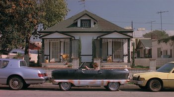 Movie still from “The Big Picture” (1989), directed by Christopher Guest – An old car parked in front of a house; Wide shot, Low angle