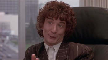 Movie still from “The Big Picture” (1989), directed by Christopher Guest – A man in a striped suit and curly hair; Close Up shot, Over the shoulder angle