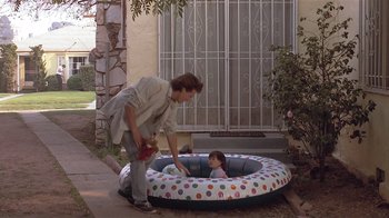 Movie still from “The Big Picture” (1989), directed by Christopher Guest – A woman and a little girl in an inflatable pool; Wide shot, High angle
