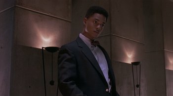 Movie still from “The Big Picture” (1989), directed by Christopher Guest – A man in a suit and bow tie standing next to a wall; Medium shot, Low angle