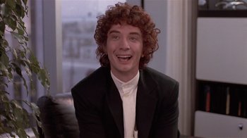 Movie still from “The Big Picture” (1989), directed by Christopher Guest – A man with curly red hair smiling for the camera; Close Up shot, Over the shoulder angle