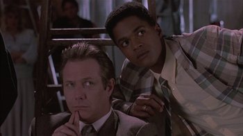 Movie still from “The Big Picture” (1989), directed by Christopher Guest – A man and a man in a suit sitting next to each other; Close Up shot, Low angle