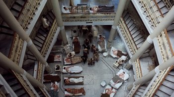 Movie still from “The Big Red One” (1980), directed by Samuel Fuller – An overhead view of a group of people laying on beds in a building; Extreme Wide shot, Overhead angle