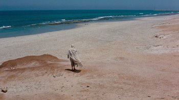 Movie still from “The Big Red One” (1980), directed by Samuel Fuller – A man walking on the beach with a towel over his head; Extreme Wide shot, High angle