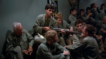 Movie still from “The Big Red One” (1980), directed by Samuel Fuller – A group of men sitting next to each other holding guns; Medium shot, High angle