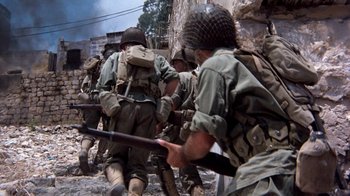 Movie still from “The Big Red One” (1980), directed by Samuel Fuller – A group of men in fatigues are marching through the rubble; Wide shot, High angle