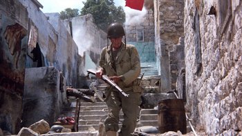 Movie still from “The Big Red One” (1980), directed by Samuel Fuller – A man in a military uniform is holding a gun; Wide shot, Low angle