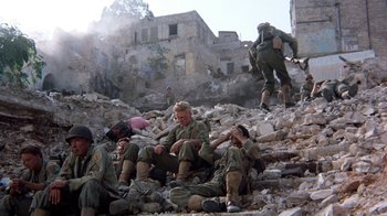 Movie still from “The Big Red One” (1980), directed by Samuel Fuller – A group of men sitting on top of a pile of rubble; Wide shot, High angle
