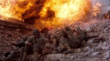 Movie still from “The Big Red One” (1980), directed by Samuel Fuller – A group of men sitting on top of a pile of rocks; Wide shot, High angle