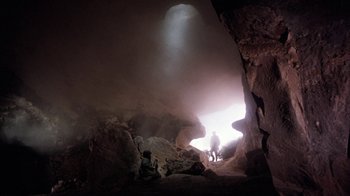Movie still from “The Big Red One” (1980), directed by Samuel Fuller – A person standing in a cave with light coming from it; Extreme Wide shot, Low angle