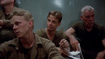 Movie still from “The Big Red One” (1980), directed by Samuel Fuller – A group of men sitting next to each other on a wall; Medium shot, Low angle
