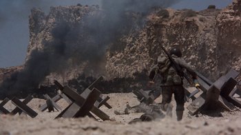Movie still from “The Big Red One” (1980), directed by Samuel Fuller – A soldier is walking through a field with a gun; Wide shot, High angle