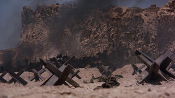 Movie still from “The Big Red One” (1980), directed by Samuel Fuller – A group of metal crosses sitting in the sand; Extreme Wide shot, High angle