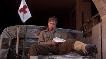 Movie still from “The Big Red One” (1980), directed by Samuel Fuller – A man sitting on the back of a truck holding a book; Medium shot, Low angle