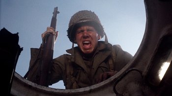 Movie still from “The Big Red One” (1980), directed by Samuel Fuller – A man with a helmet and a gun in his hand; Close Up shot, Low angle
