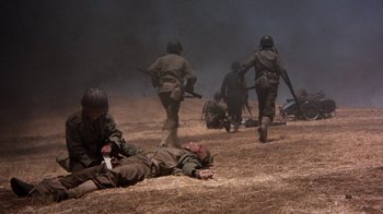 Movie still from “The Big Red One” (1980), directed by Samuel Fuller – A group of soldiers running across a dirt field; Wide shot, High angle