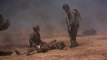 Movie still from “The Big Red One” (1980), directed by Samuel Fuller – Two men in uniforms are standing over an injured soldier; Wide shot, High angle