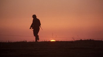 Movie still from “The Big Red One” (1980), directed by Samuel Fuller – A man walking across a field at sunset; Wide shot, Low angle