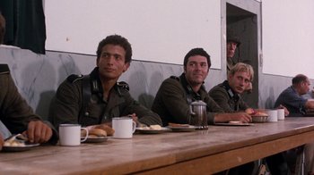 Movie still from “The Big Red One” (1980), directed by Samuel Fuller – A group of men sitting at a table with plates of food on it; Medium shot, Over the shoulder angle