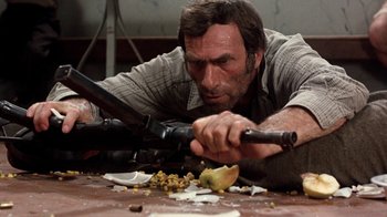 Movie still from “The Big Red One” (1980), directed by Samuel Fuller – A man with a gun and a knife on a table; Close Up shot, Low angle