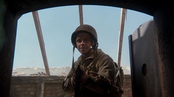 Movie still from “The Big Red One” (1980), directed by Samuel Fuller – A man wearing a helmet and holding a rifle; Medium shot, Over the shoulder angle