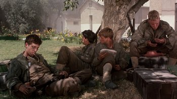 Movie still from “The Big Red One” (1980), directed by Samuel Fuller – A group of men sitting next to each other on the grass; Medium shot, High angle
