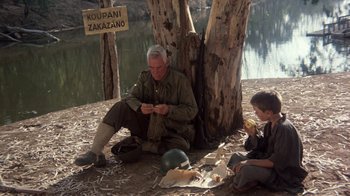 Movie still from “The Big Red One” (1980), directed by Samuel Fuller – An old man sitting next to a tree while a young boy sits next to him; Wide shot, High angle
