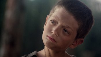 Movie still from “The Big Red One” (1980), directed by Samuel Fuller – A young boy with a chain around his neck; Close Up shot, Over the shoulder angle