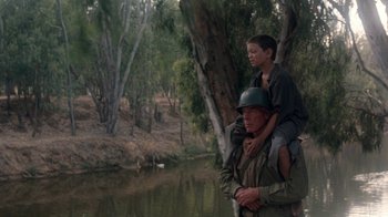 Movie still from “The Big Red One” (1980), directed by Samuel Fuller – A man and a boy are standing next to a body of water; Medium shot, Over the shoulder angle