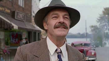 Movie still from “The Big Town” (1987), directed by Harold Becker – A person wearing a suit and a hat; Close Up shot, Low angle
