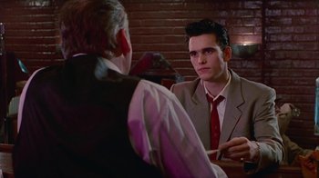 Movie still from “The Big Town” (1987), directed by Harold Becker – A man wearing a suit and tie talking to another man wearing a suit and tie; Medium shot, Over the shoulder angle