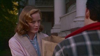 Movie still from “The Big Town” (1987), directed by Harold Becker – A woman holding a paper bag on the sidewalk; Close Up shot, Over the shoulder angle