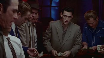 Movie still from “The Big Town” (1987), directed by Harold Becker – A group of men standing around each other holding money; Medium shot, Low angle