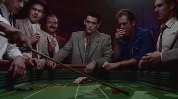 Movie still from “The Big Town” (1987), directed by Harold Becker – A group of men sitting at a table with a craps table in front of them; Medium shot, High angle