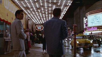Movie still from “The Big Town” (1987), directed by Harold Becker – A man walking down a street at night; Wide shot, Low angle