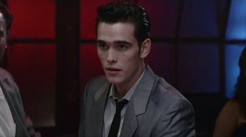 Movie still from “The Big Town” (1987), directed by Harold Becker – A man in a suit and tie looking at the camera; Close Up shot, High angle