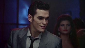 Movie still from “The Big Town” (1987), directed by Harold Becker – A man in a suit and tie next to a woman in a black dress; Close Up shot, Over the shoulder angle