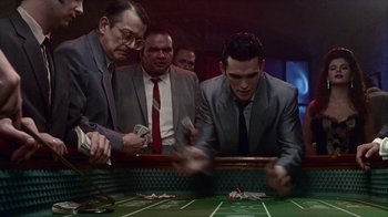 Movie still from “The Big Town” (1987), directed by Harold Becker – A group of men in suits playing a game of craps; Medium shot, High angle