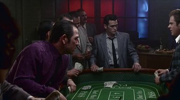 Movie still from “The Big Town” (1987), directed by Harold Becker – A group of men standing around a table with money; Wide shot, High angle