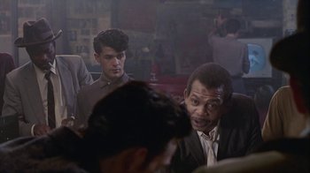 Movie still from “The Big Town” (1987), directed by Harold Becker – Two men sitting in front of each other in a room; Medium shot, Over the shoulder angle