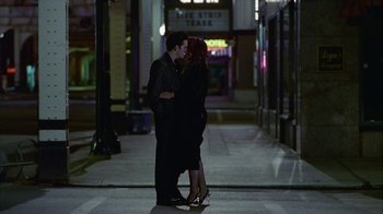 Movie still from “The Big Town” (1987), directed by Harold Becker – A man and a woman kissing on the sidewalk; Wide shot, High angle