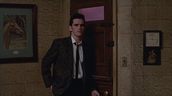 Movie still from “The Big Town” (1987), directed by Harold Becker – A man in a suit standing in front of a door; Medium shot, Low angle