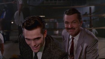Movie still from “The Big Town” (1987), directed by Harold Becker – A man and a man in a suit and tie smiling; Medium shot, Low angle