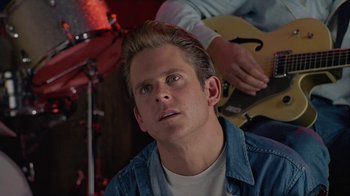 Movie still from “The Big Town” (1987), directed by Harold Becker – A young man is looking up while playing a guitar; Close Up shot, Over the shoulder angle