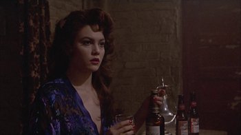 Movie still from “The Big Town” (1987), directed by Harold Becker – A woman sitting at a table holding a glass of beer; Close Up shot, Over the shoulder angle