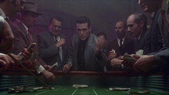 Movie still from “The Big Town” (1987), directed by Harold Becker – A group of men standing around a table with money; Medium shot, High angle