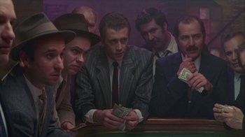 Movie still from “The Big Town” (1987), directed by Harold Becker – A group of men sitting around a pool table holding money; Medium shot, High angle