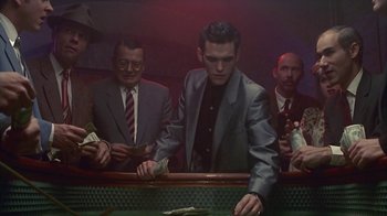 Movie still from “The Big Town” (1987), directed by Harold Becker – A group of men standing around a table; Medium shot, Low angle